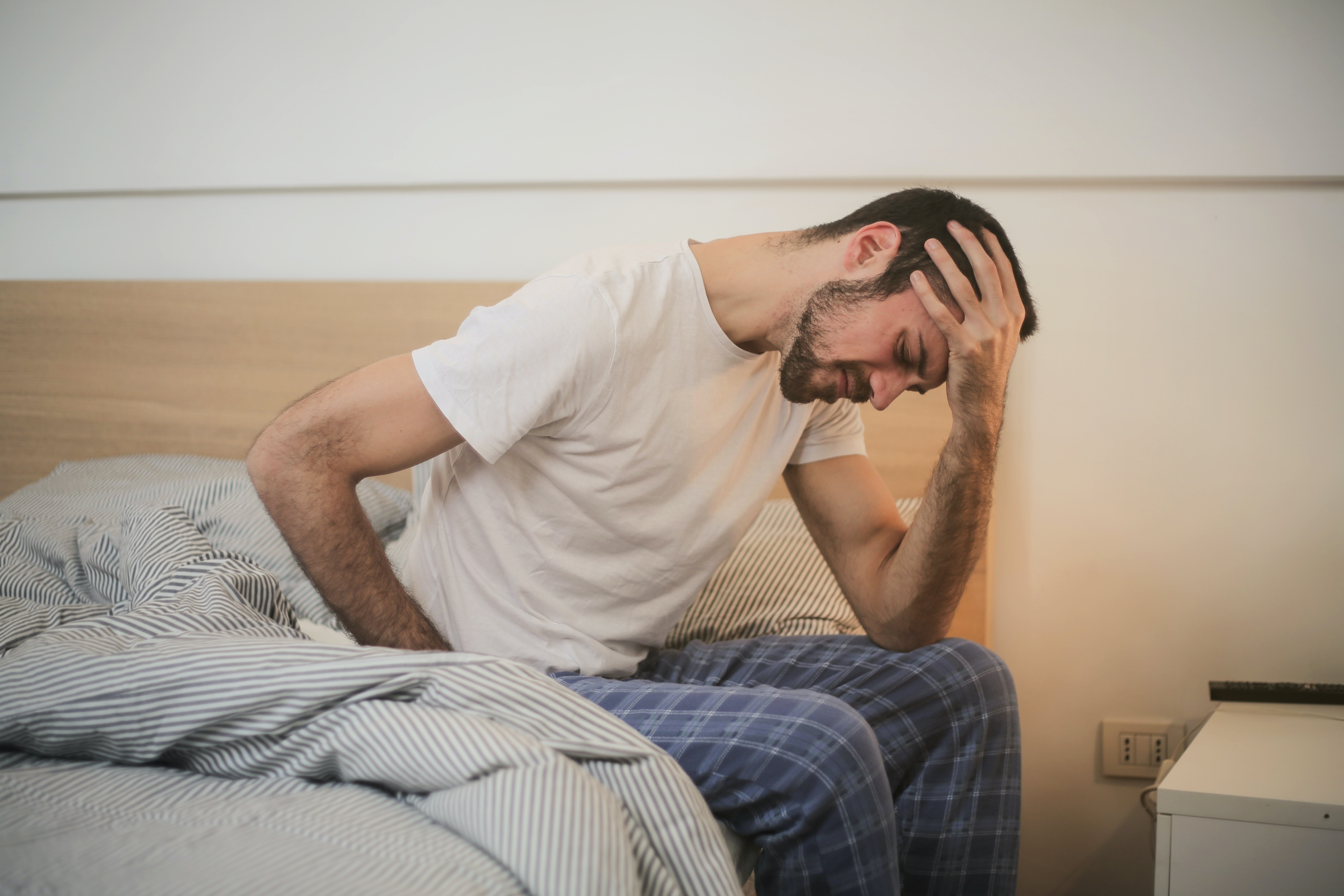 man sitting on bed with head in hands