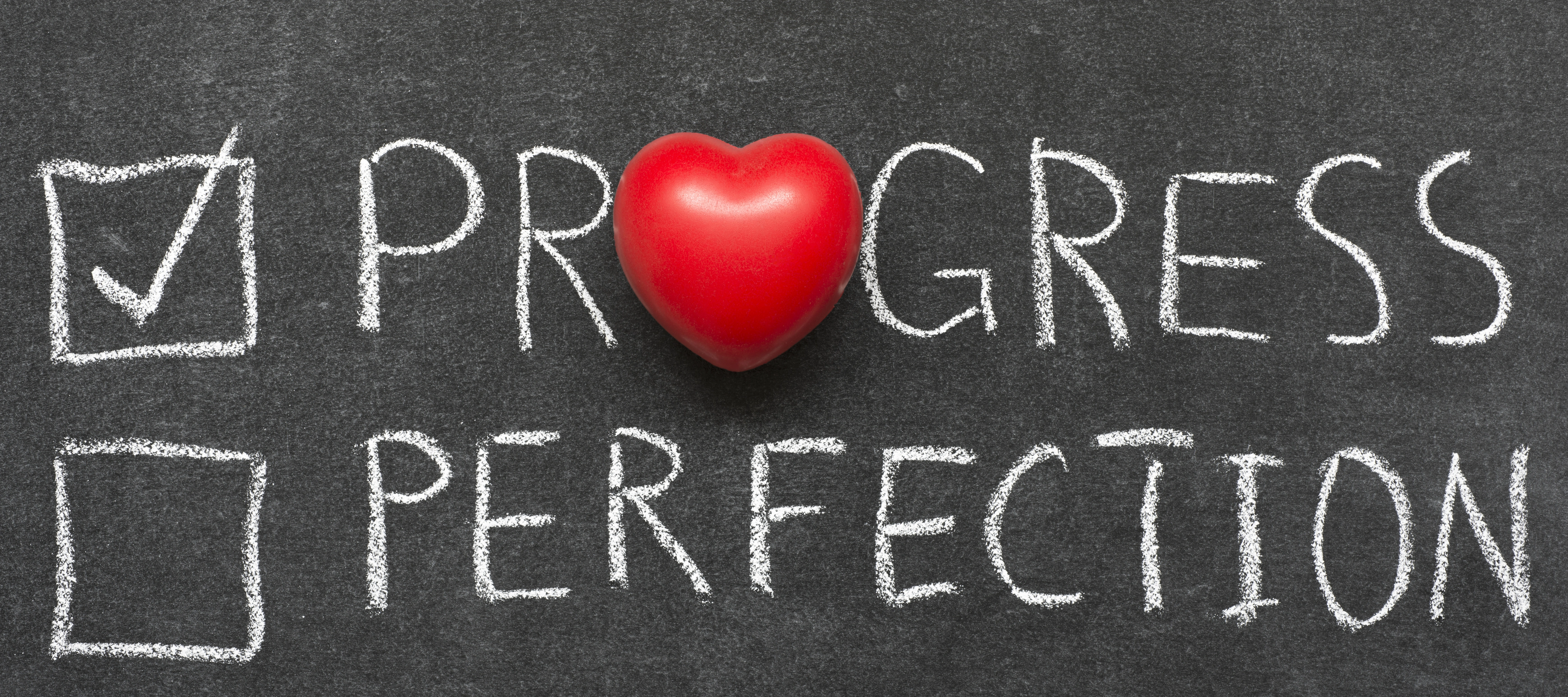 chalkboard with progress not perfection written on it